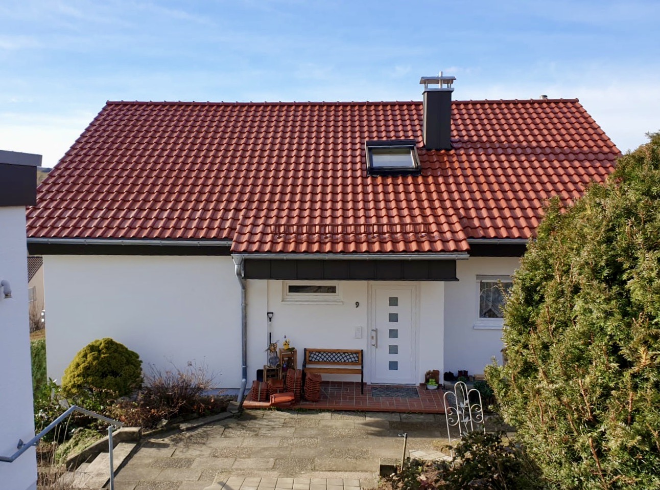 Saniertes rotes Ziegeldach mit Dachfenster und Kaminverkleidung