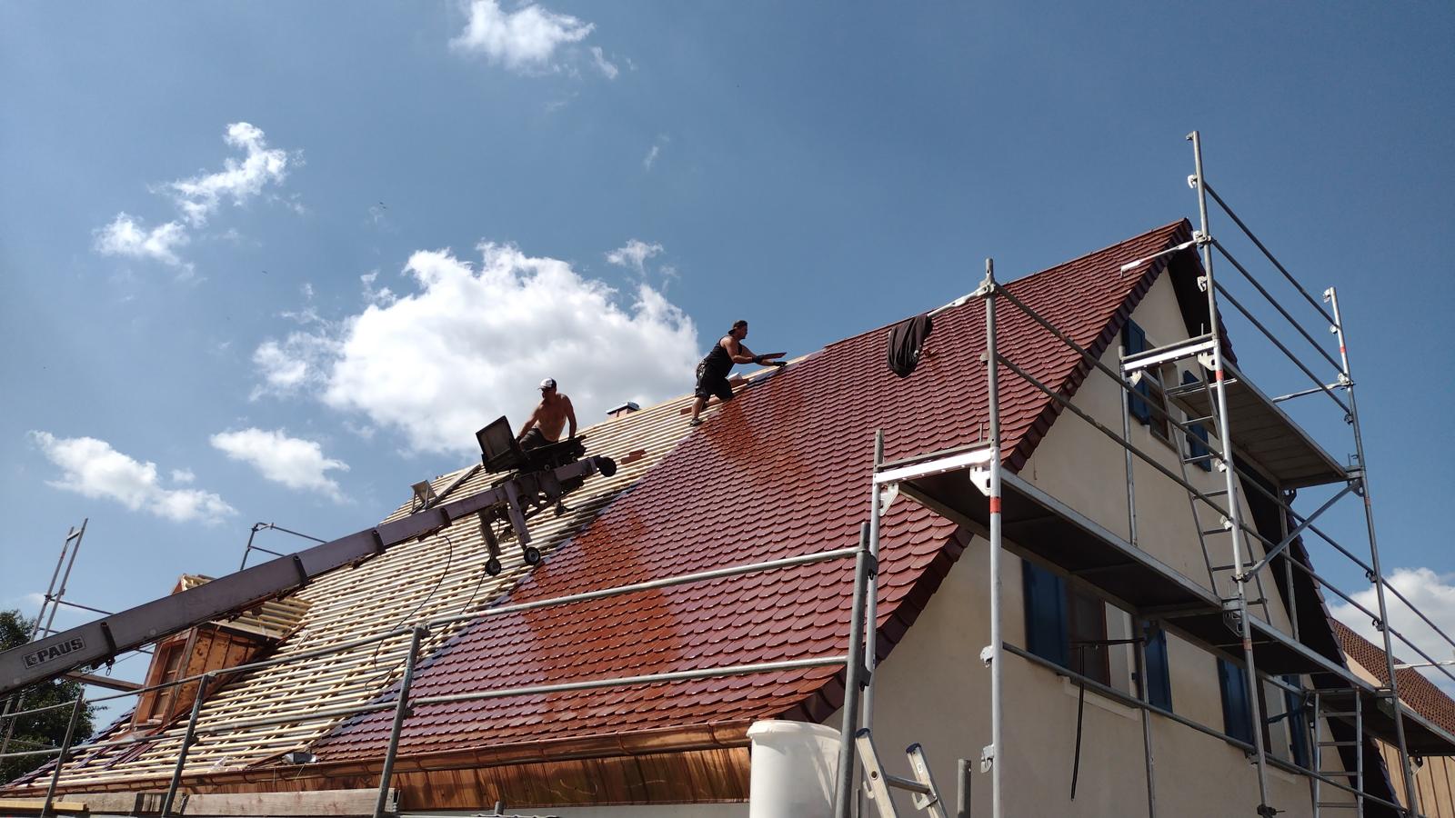 Dachdecker bei der Neueindeckung eines roten Ziegeldachs